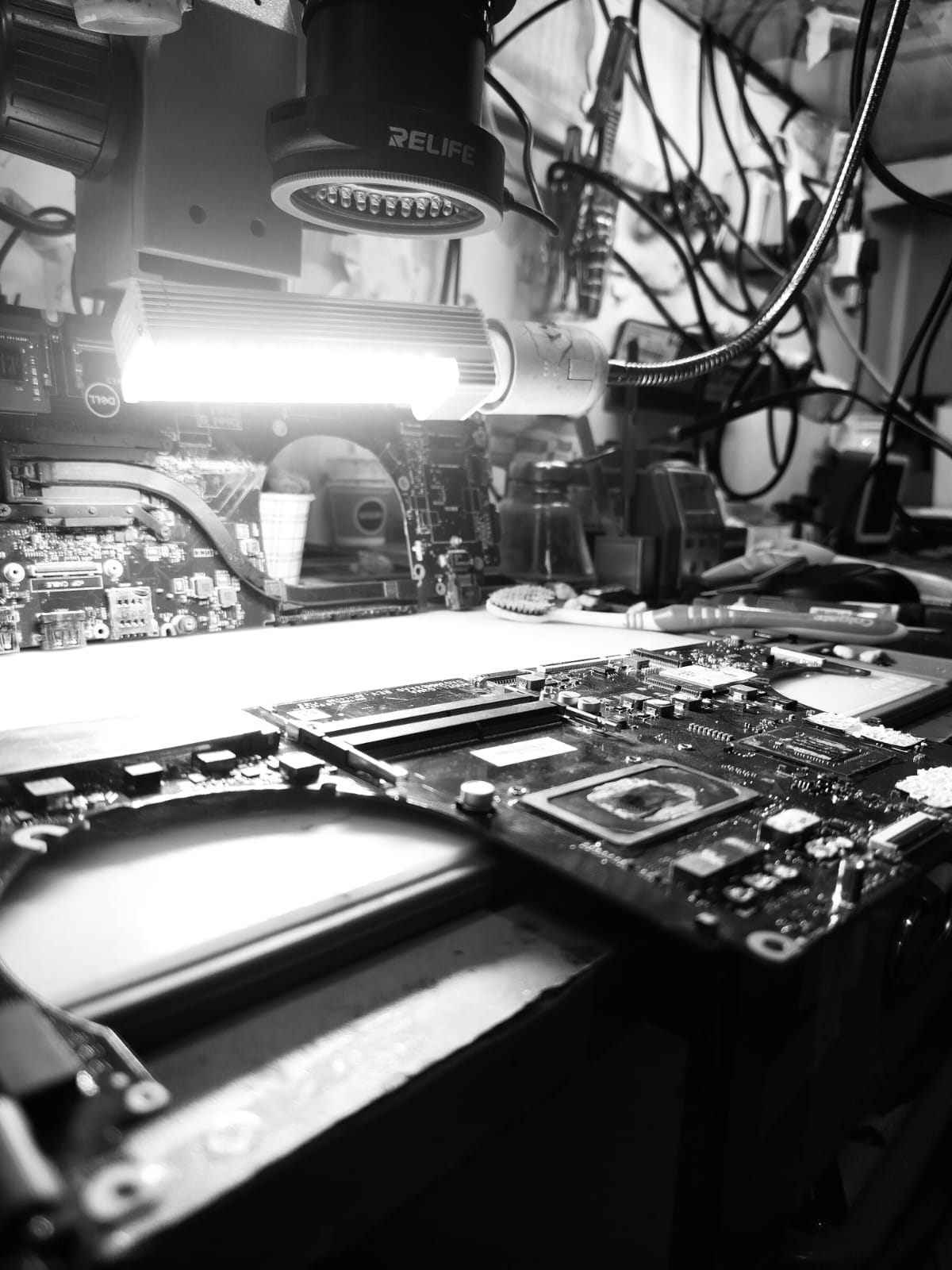Close-up of a repair bench with exposed laptop circuitry under service tools